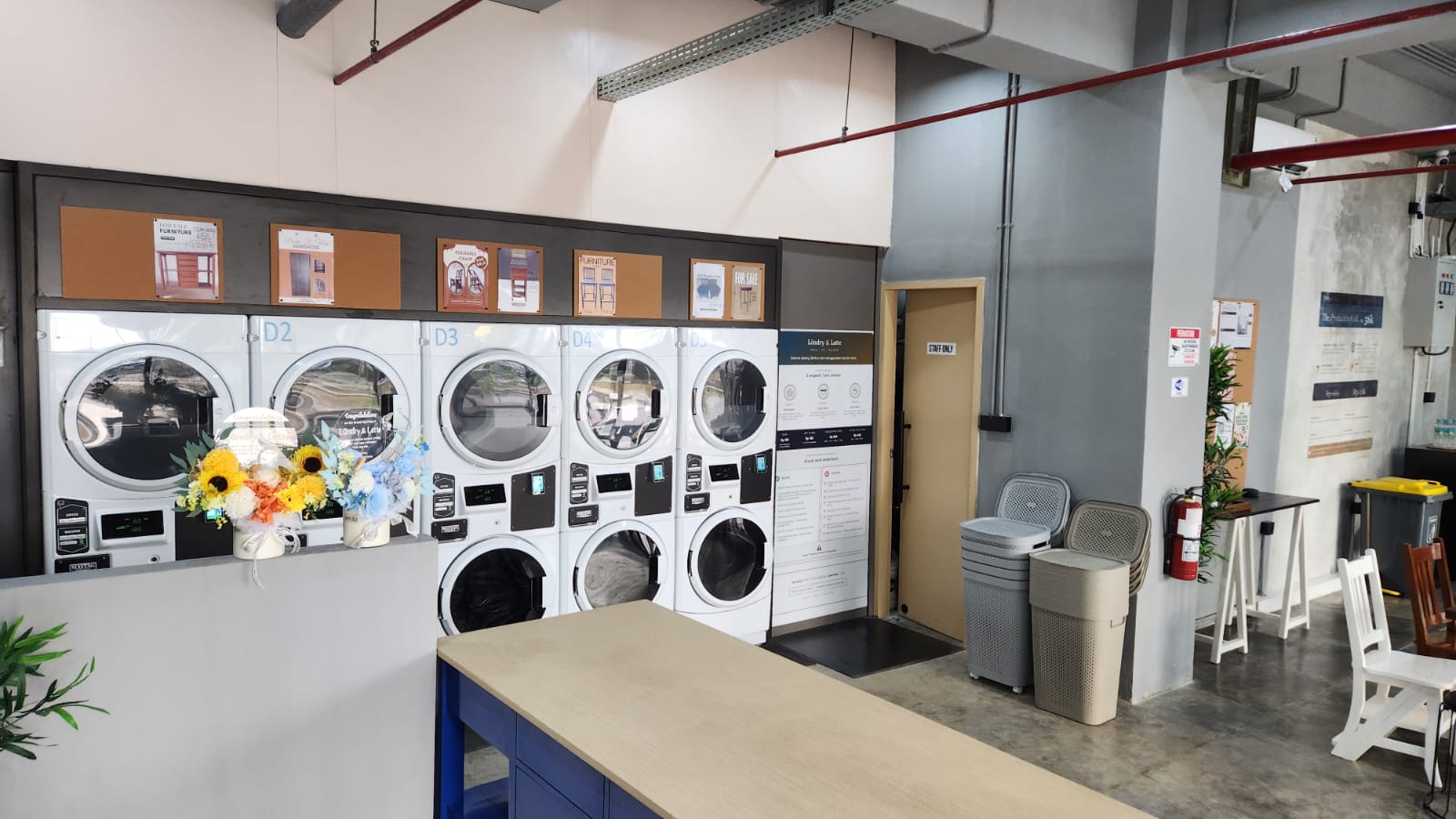 Mesin cuci dan pengering Maytag Commercial D1 sampai D5, dengan papan cara pakai di sebelahnya
