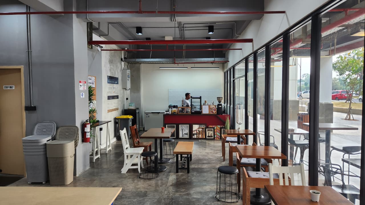 Area duduk ber-AC dengan meja dan bangku menghadap jendela